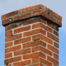 A slightly damaged and discolored brick chimney