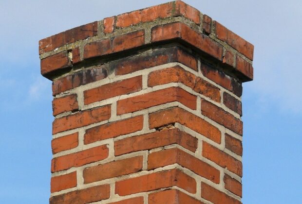 A slightly damaged and discolored brick chimney